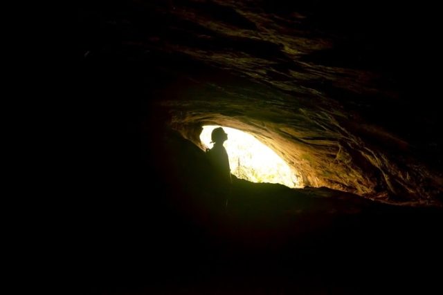 Σκοτεινό σπήλαιο με φωτεινή έξοδο στην οποία αχνοφαίνεται σκια γυναίκας
