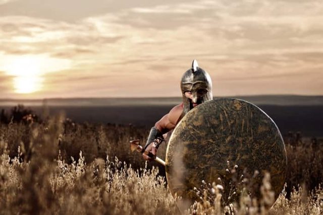 αρχαίος Έλληνας στρατιώτης κρύβεται πίσω από την ασπίδα του