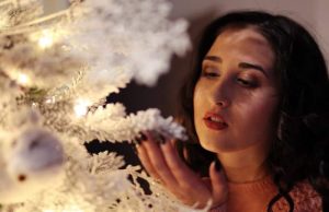 1 – 7 Ιανουαρίου: Ιδανική περίοδος Υλοποίησης Ευχών κοπέλα κοντά στο χριστουγεννιάτικο δέντρο