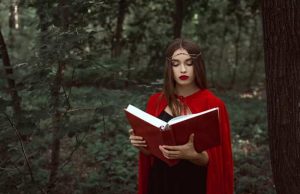 Όλη η Μαγεία Βρίσκεται στα Δάχτυλα του Χεριού μας Κοπέλα με κόκκινο μανδύα διαβάζει βιβλίο με κόκκινο εξώφυλο που κρατάει με τα δάχτυλα των χεριών της