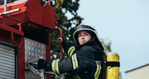 Πυροσβέστης Άναβε τη Σπίθα Ψυχικών Ικανοτήτων Γυναίκα Πυροσβέστης στο πίσω μέρος πυροσβεστικού οχήματος