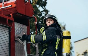 Πυροσβέστης Άναβε τη Σπίθα Ψυχικών Ικανοτήτων Γυναίκα Πυροσβέστης στο πίσω μέρος πυροσβεστικού οχήματος